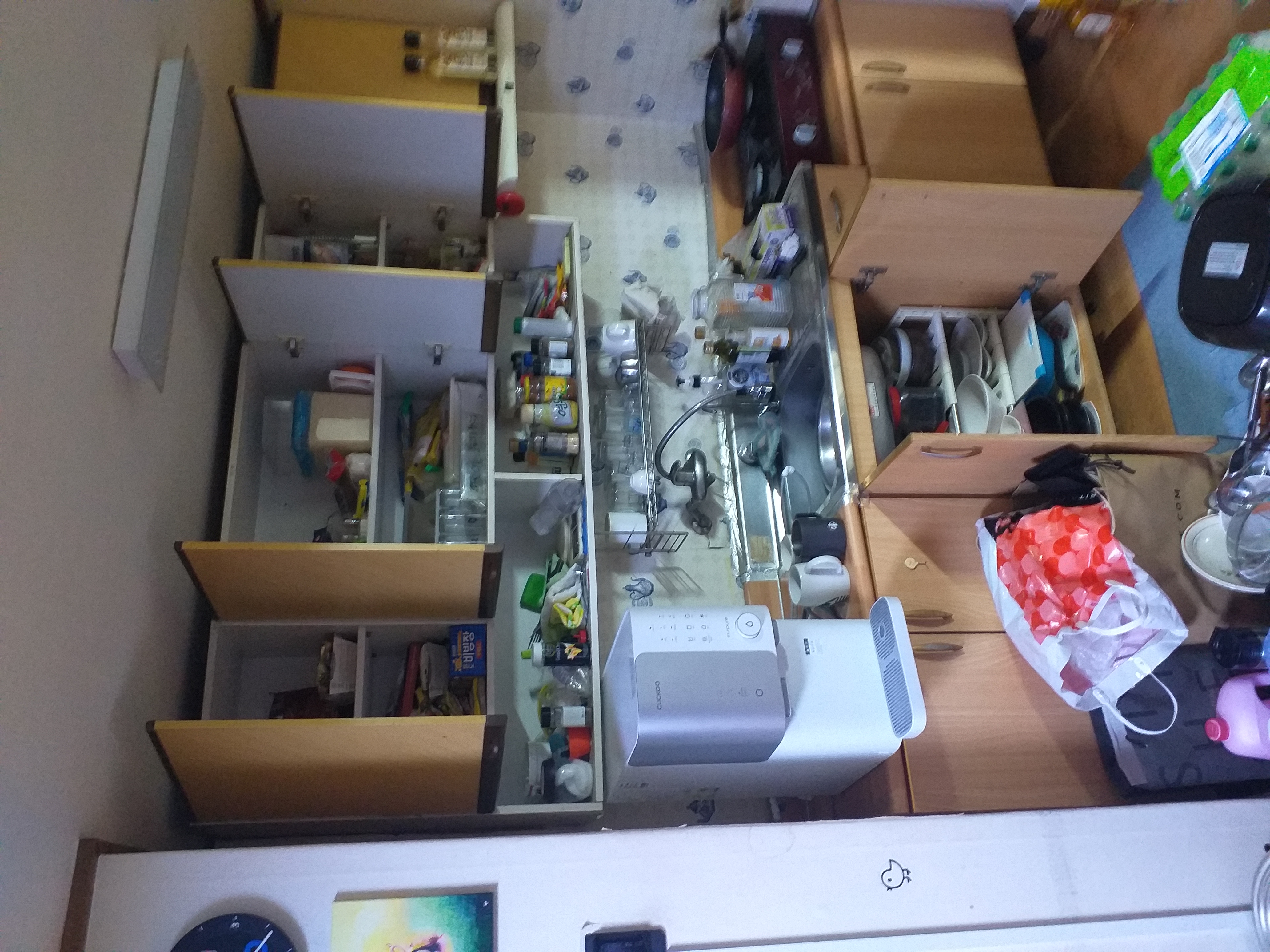 주방 수납장과 조리대에 식기와 물건이 가득한 모습