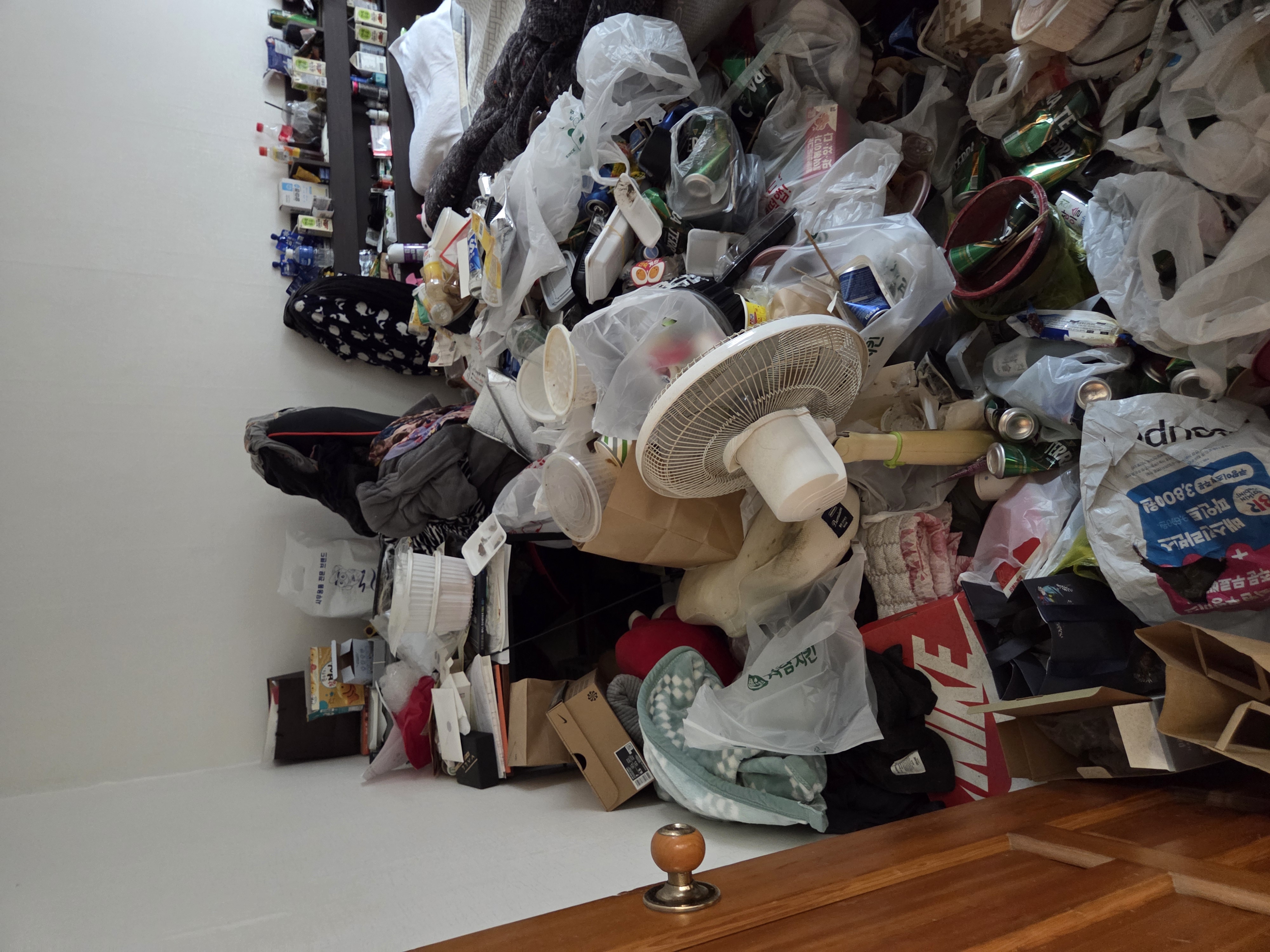 방 안에 쓰레기와 물건이 가득 쌓여 있는 모습